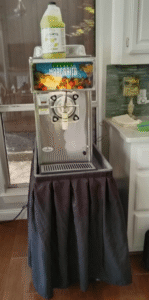 A commercial margarita machine dispensing frozen margaritas into salt-rimmed glasses at a sunny Dallas patio party. Rented from Dallas Event Rentals.